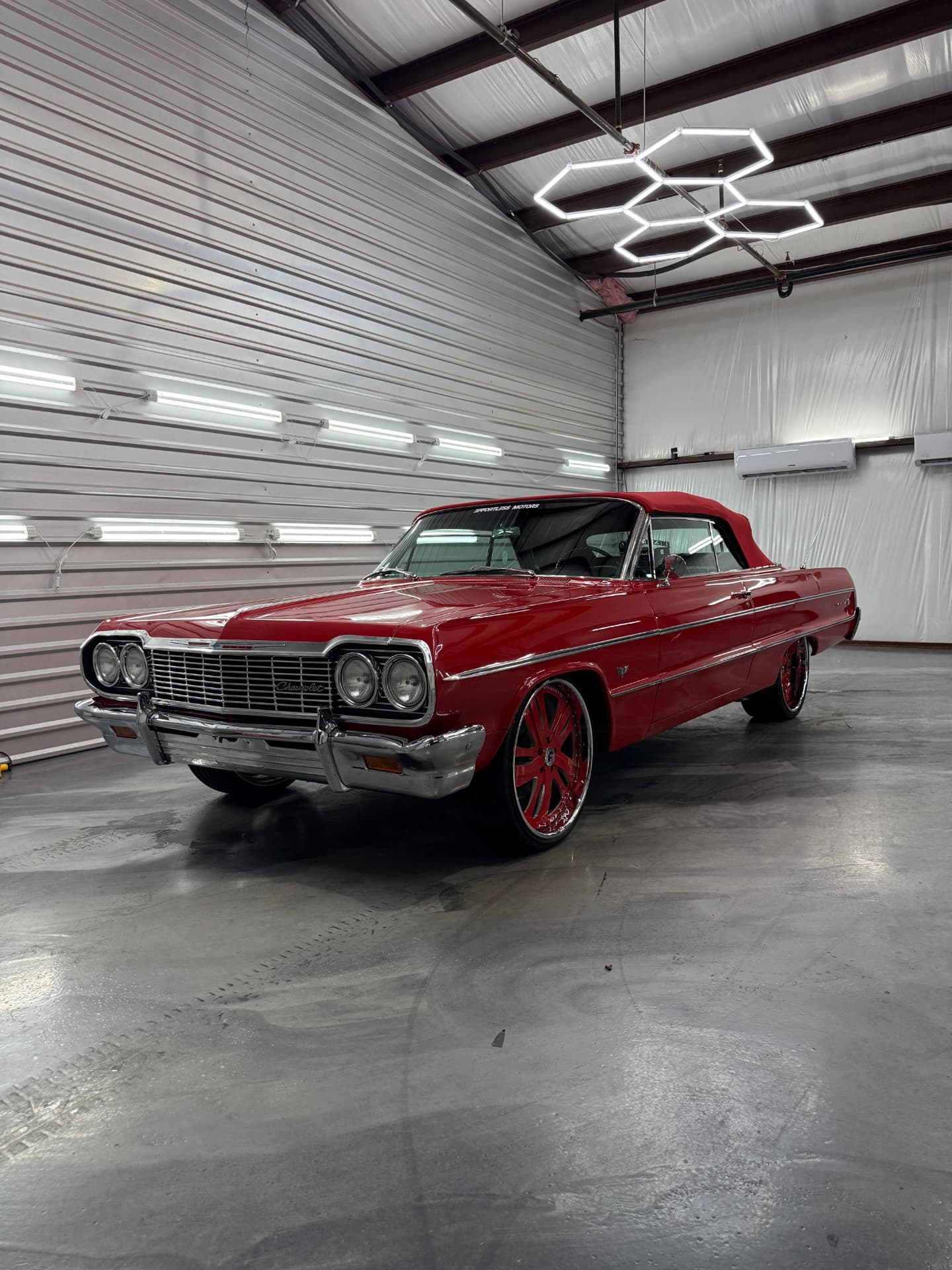 Red classic Chevrolet Impala convertible under hex lights at JJ’s Car Care in Terrell, Texas