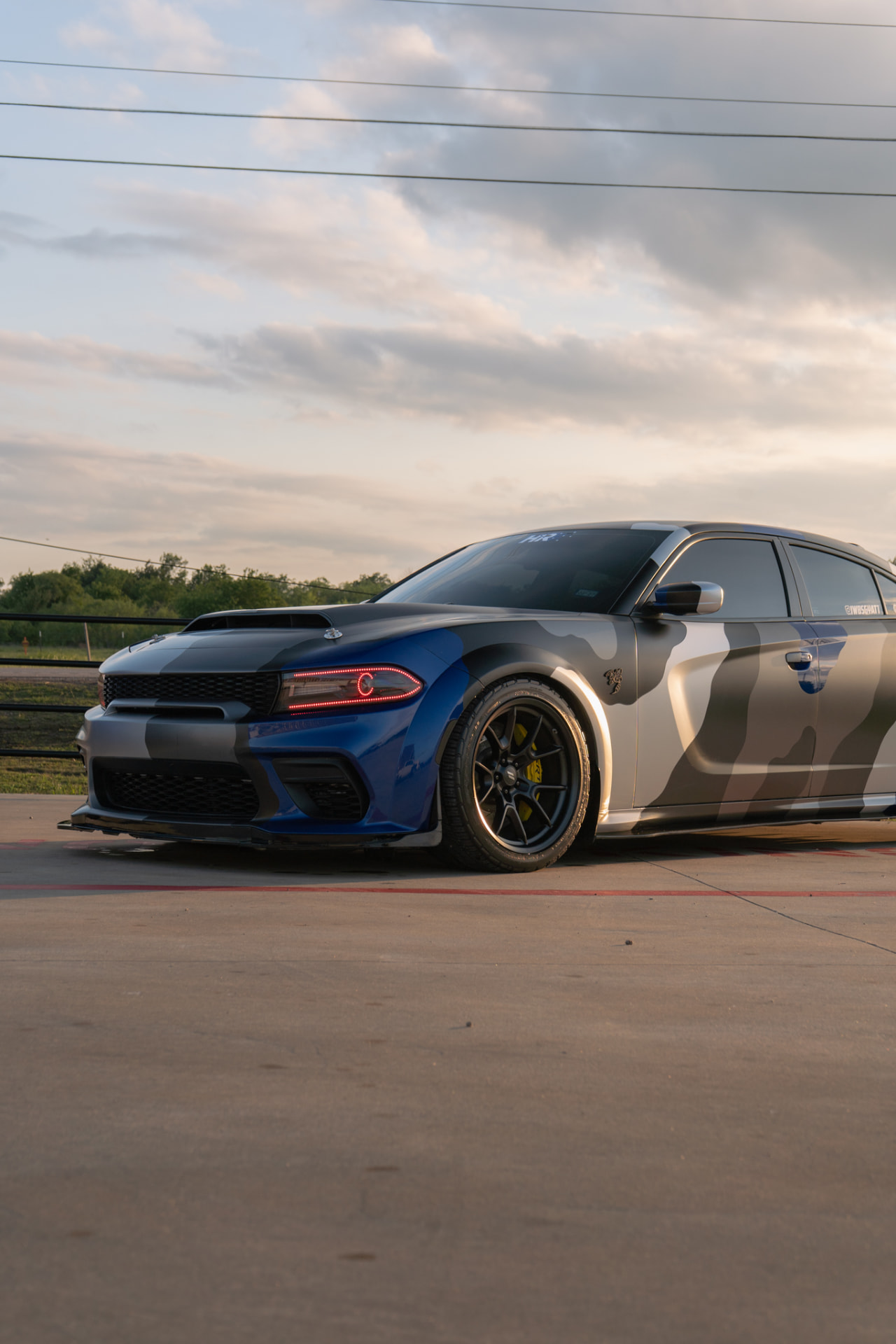 Dodge Charger with a multi-color camouflage wrap and gloss metallic blue front at JJ’s Car Care in Terrell